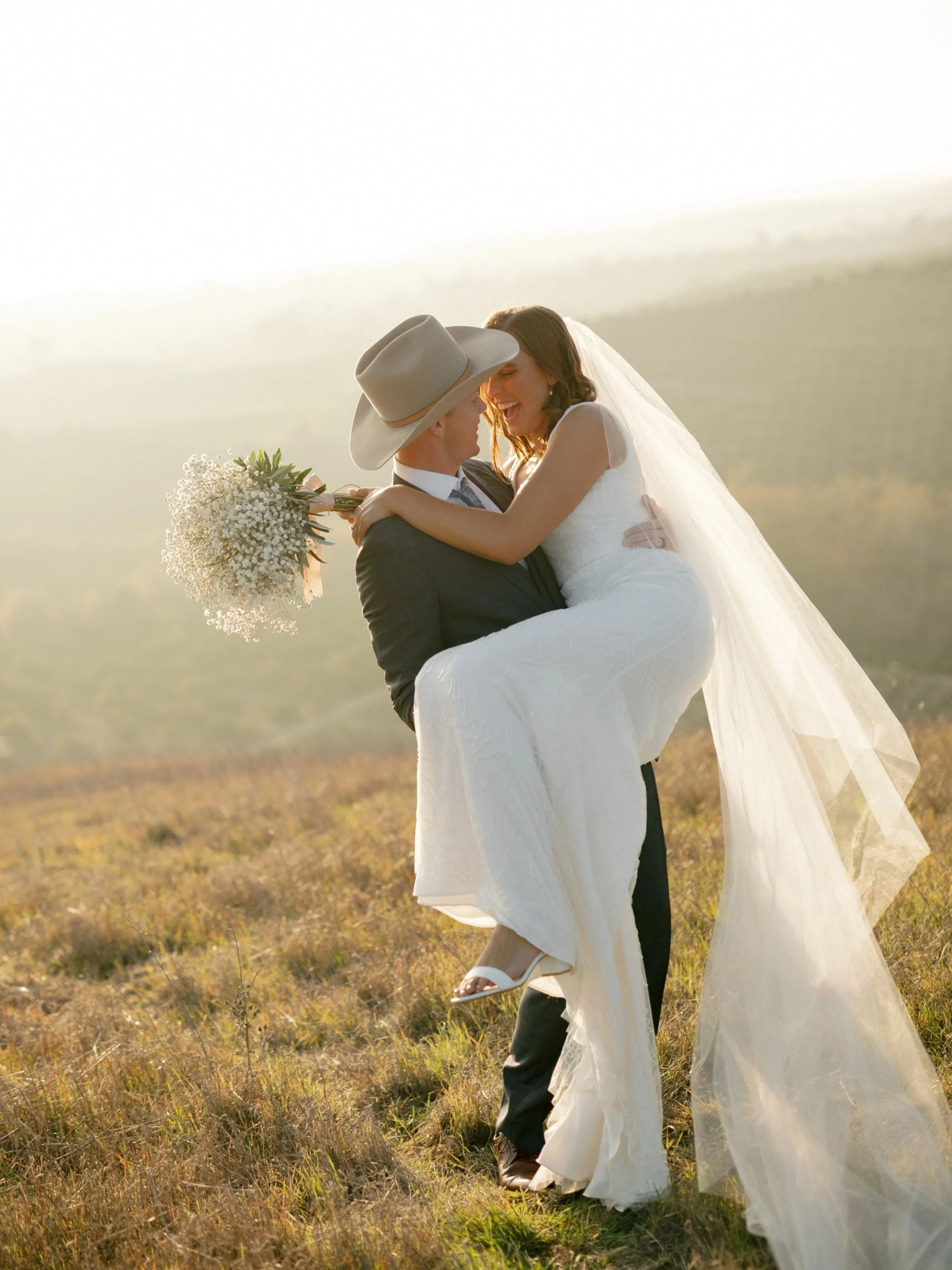 Fun loving couple on a hilltop at sunset dancing on their wedding day.  Regina Ranch wedding photographer Katie Edwards captured Regina Ranch couple smiling and having a great time.