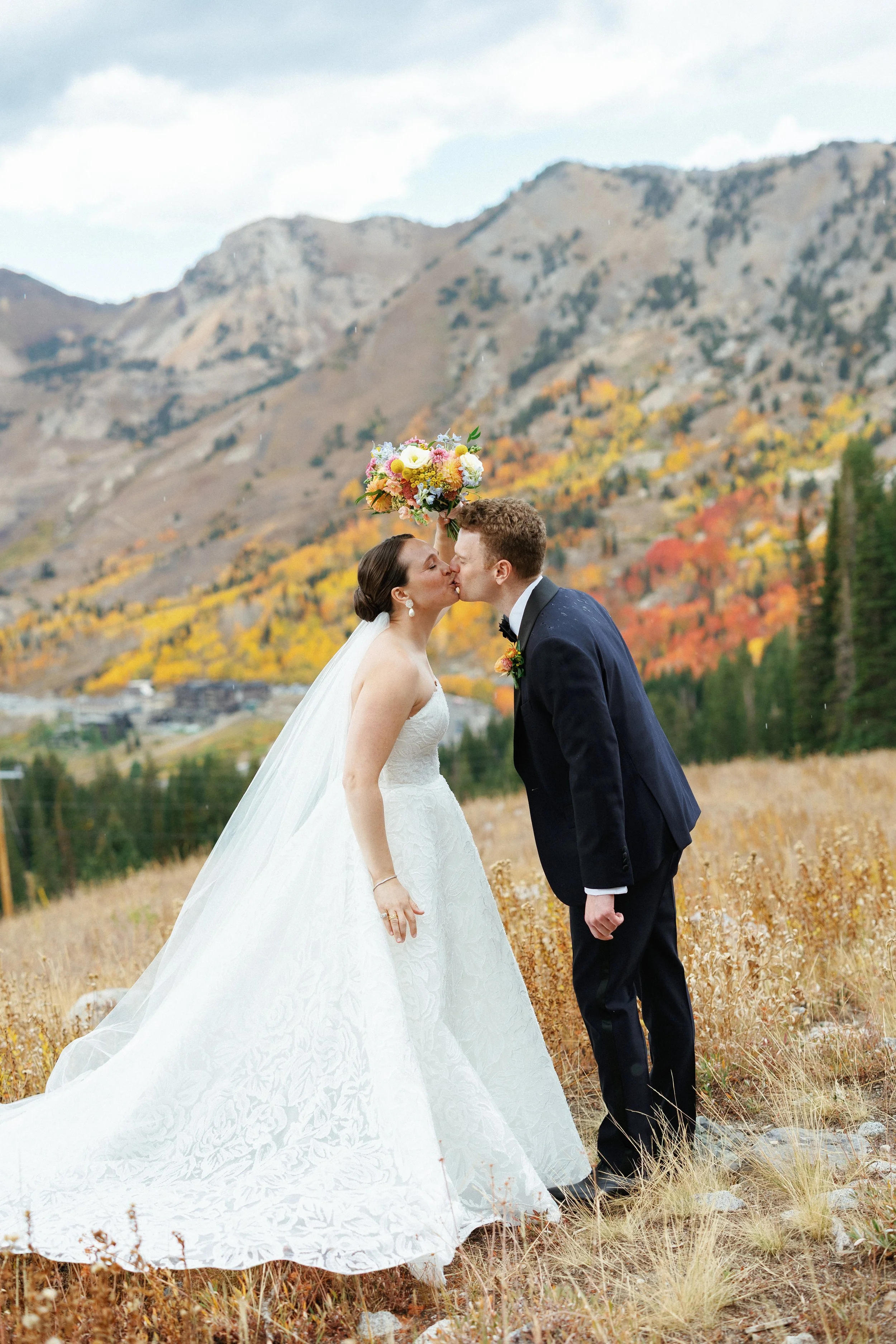 Snowpine wedding with fall colors. Couple standing on the mountain top and shielding themselves from the rain fall.  Best Salt Lake City wedding photographer Katie Edwards captured the couple great.