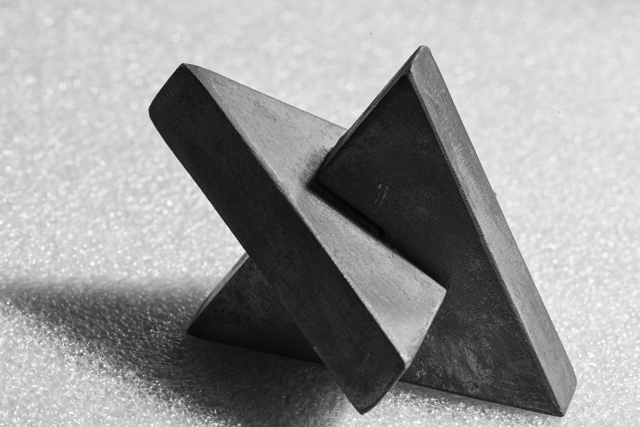 Deux formes géométriques foncées appuyées l'une contre l'autre sur une surface texturée.
