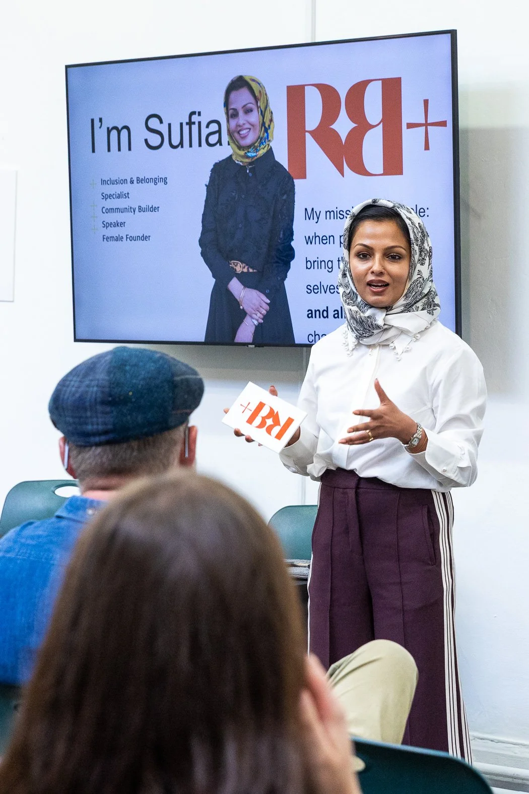 Sufia Hussain in front of a screen bearing her image and introduction, as she discussions religion, the final taboo.