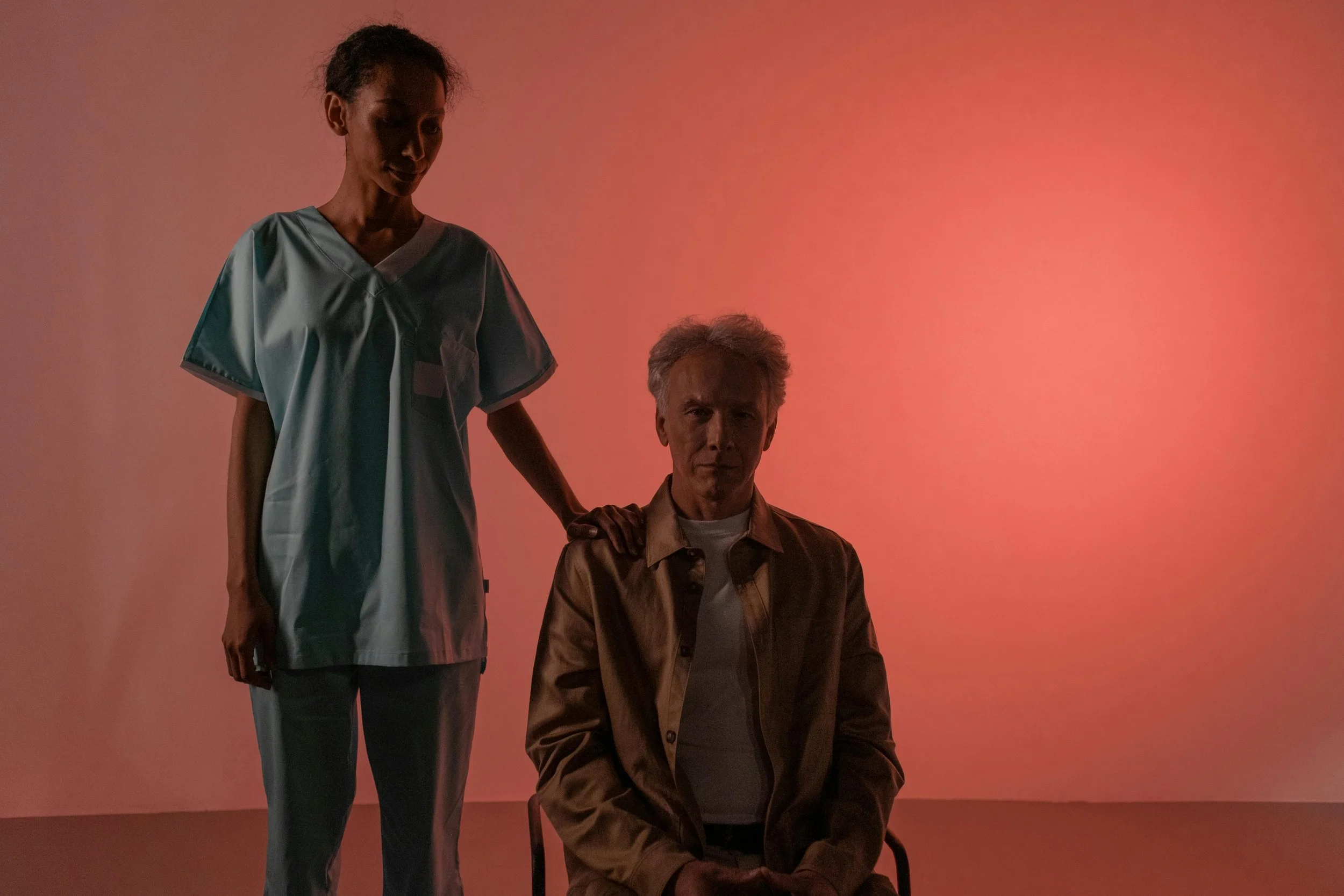 A home care professional in scrubs standing beside an older adult male client, representing compassionate senior care support services from Home to Home Services in Richmond, VA.
