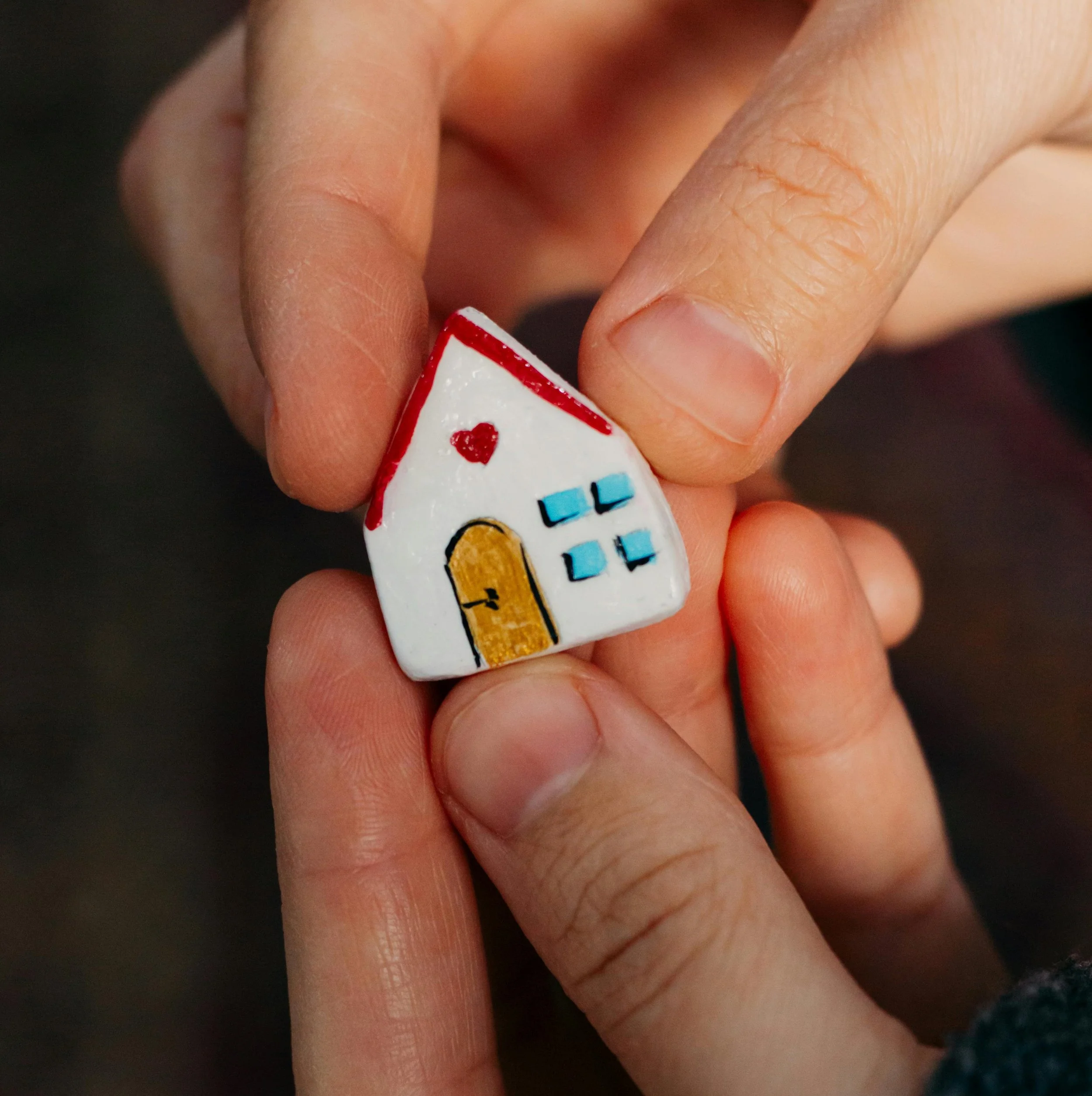 Close-up of a person's hand holding a white game die with colored dots and numbers.