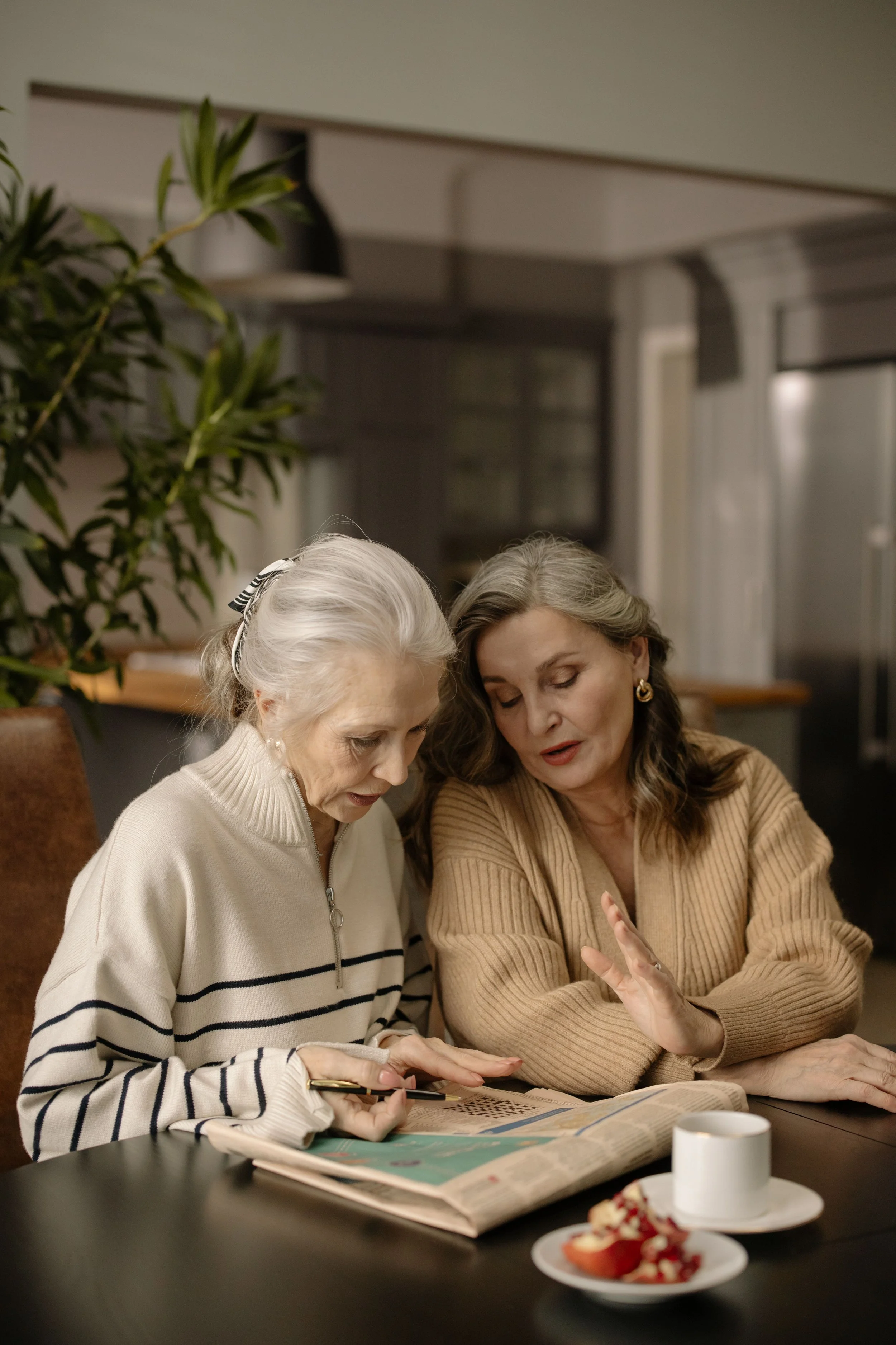 An older woman and an adult daughter reviewing documents together at a table in a warm home setting — representing the collaborative, unhurried approach to senior move planning that Home to Home Services provides for families in Richmond, VA