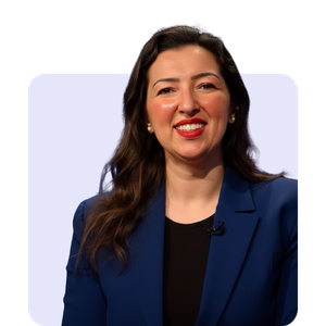 A woman with long dark hair, wearing a blue blazer and black top, smiling against a plain background.