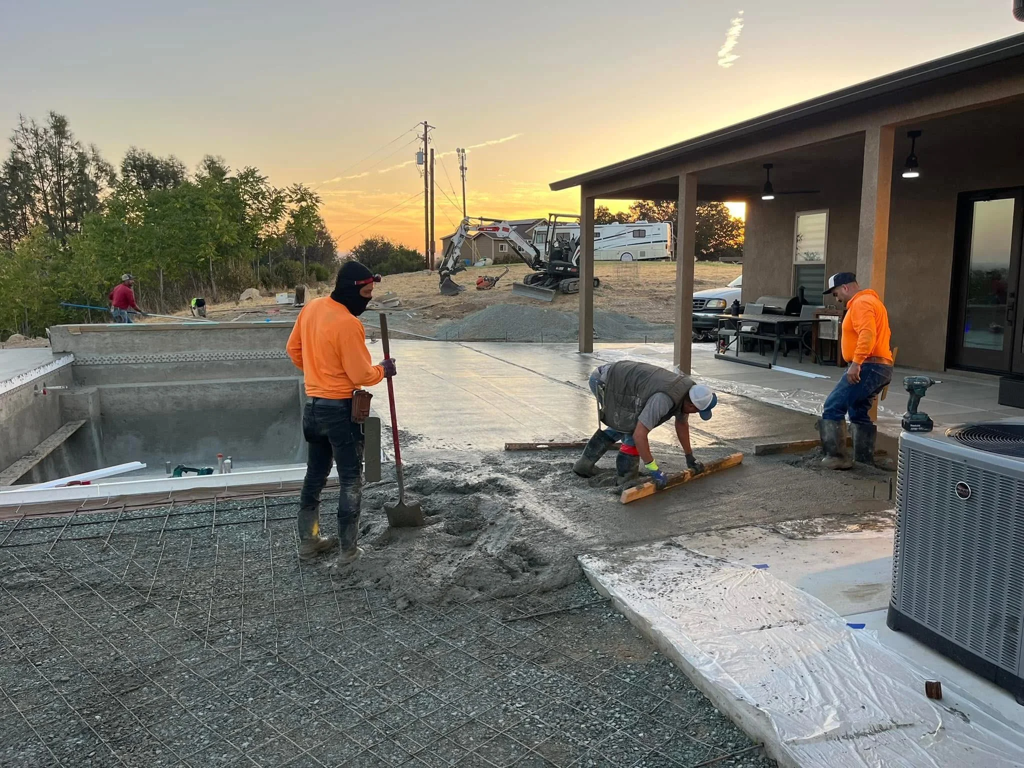 Three men laying concrete near a pool 