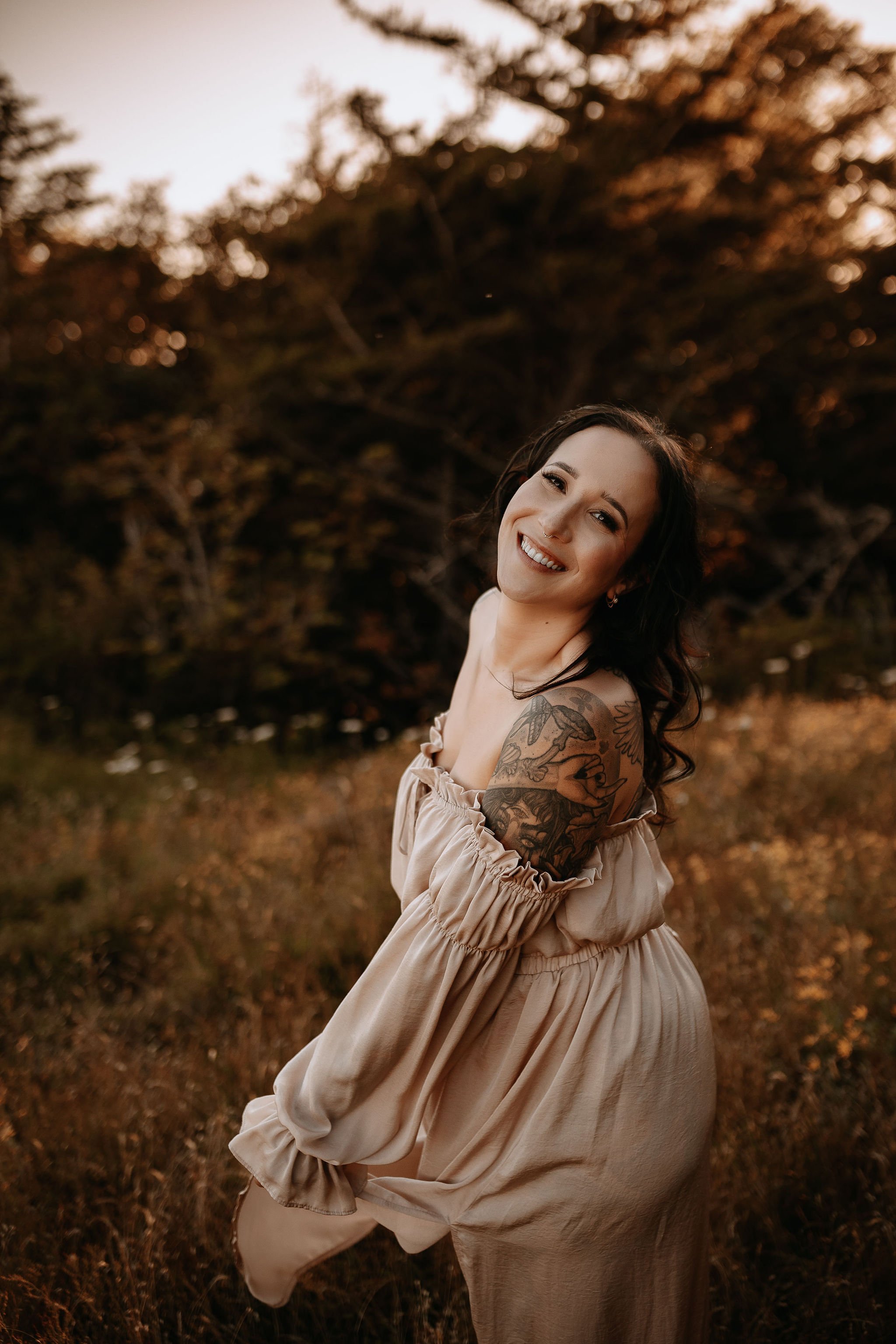 Close-up of a woman's face with light blue eyes, wearing a white headwrap and a white lace top, on a sandy beach with rocks.