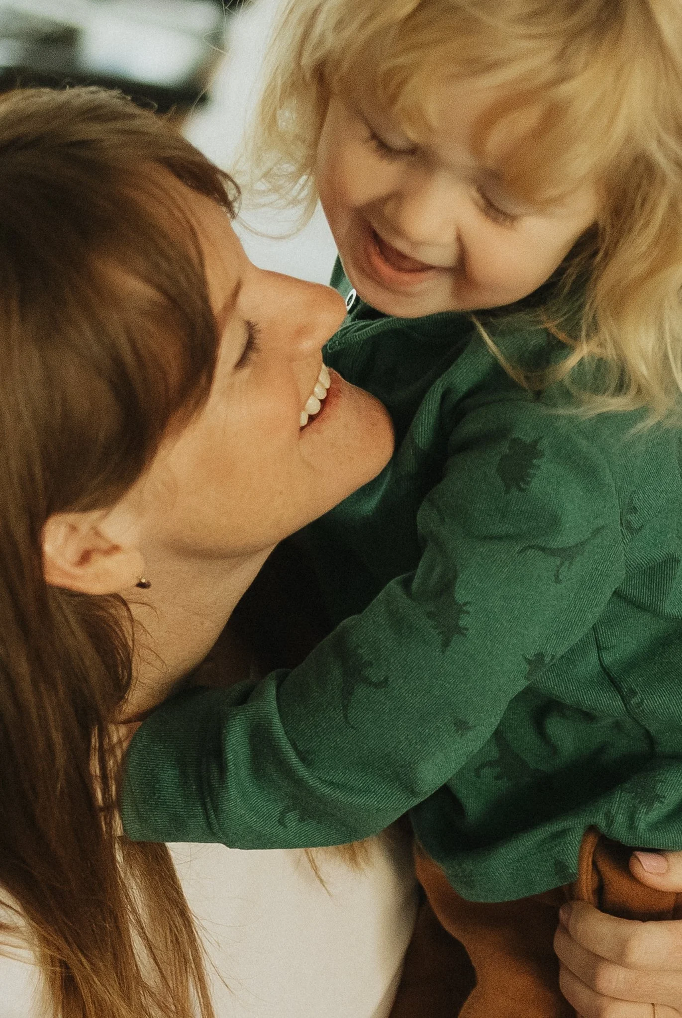 A woman and a young girl sharing a joyful moment, with their faces close and smiling.