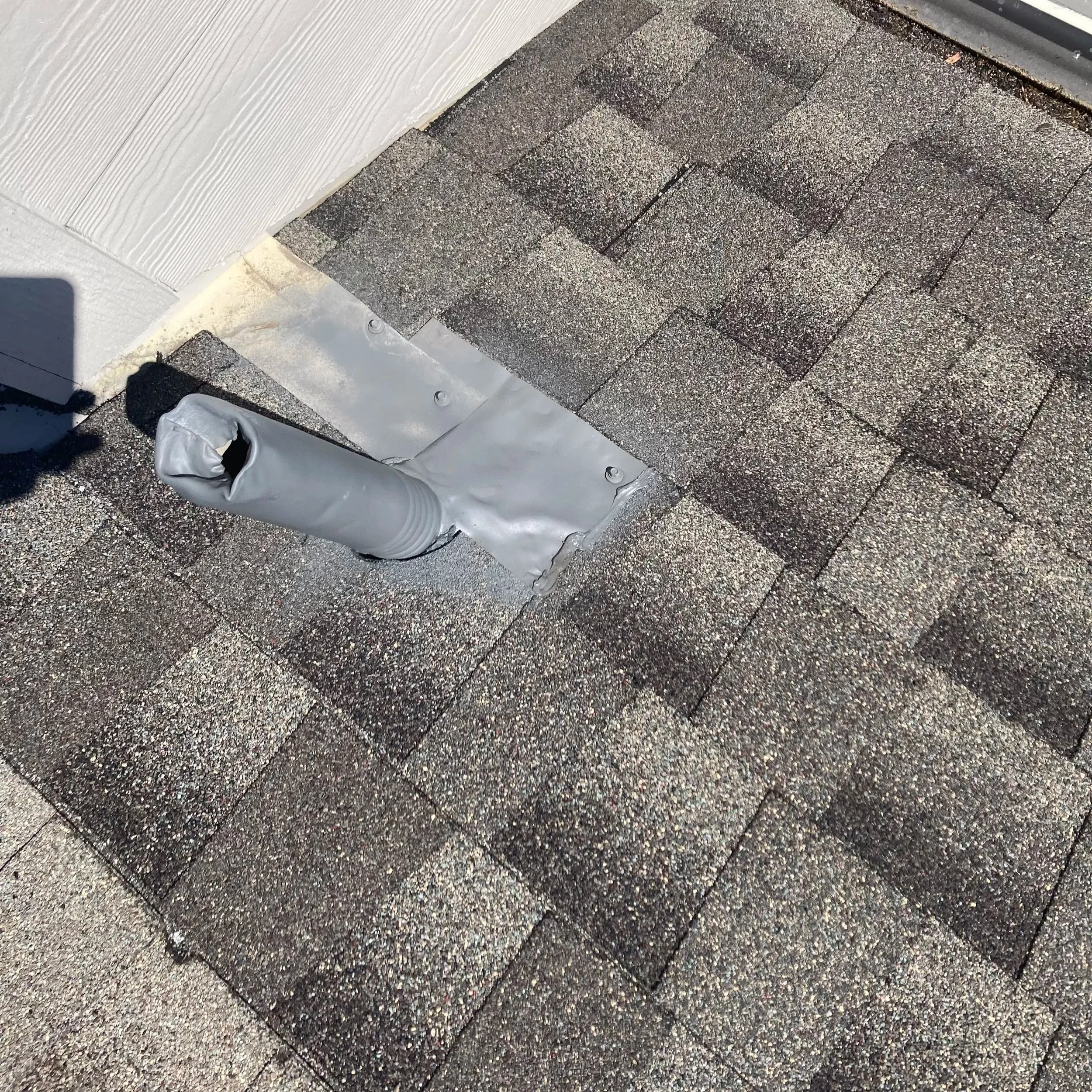 Close-up of a section of asphalt roofing shingles on a roof, showing different shades of brown and gray.