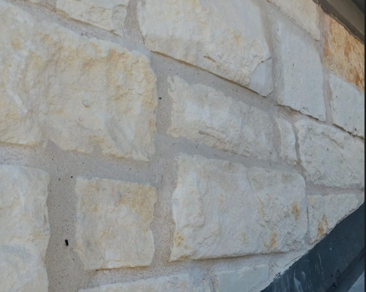 Close-up of a beige brick wall with gray mortar lines.