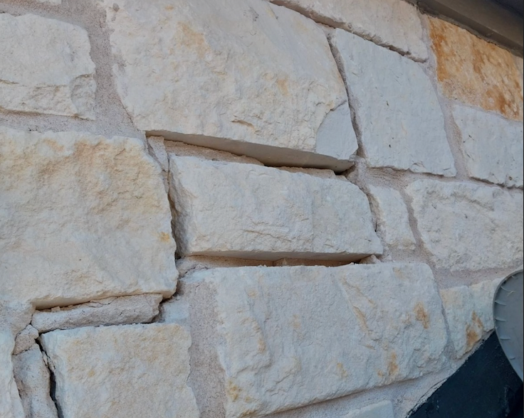 Close-up of a beige and tan stone wall with visible mortar lines.