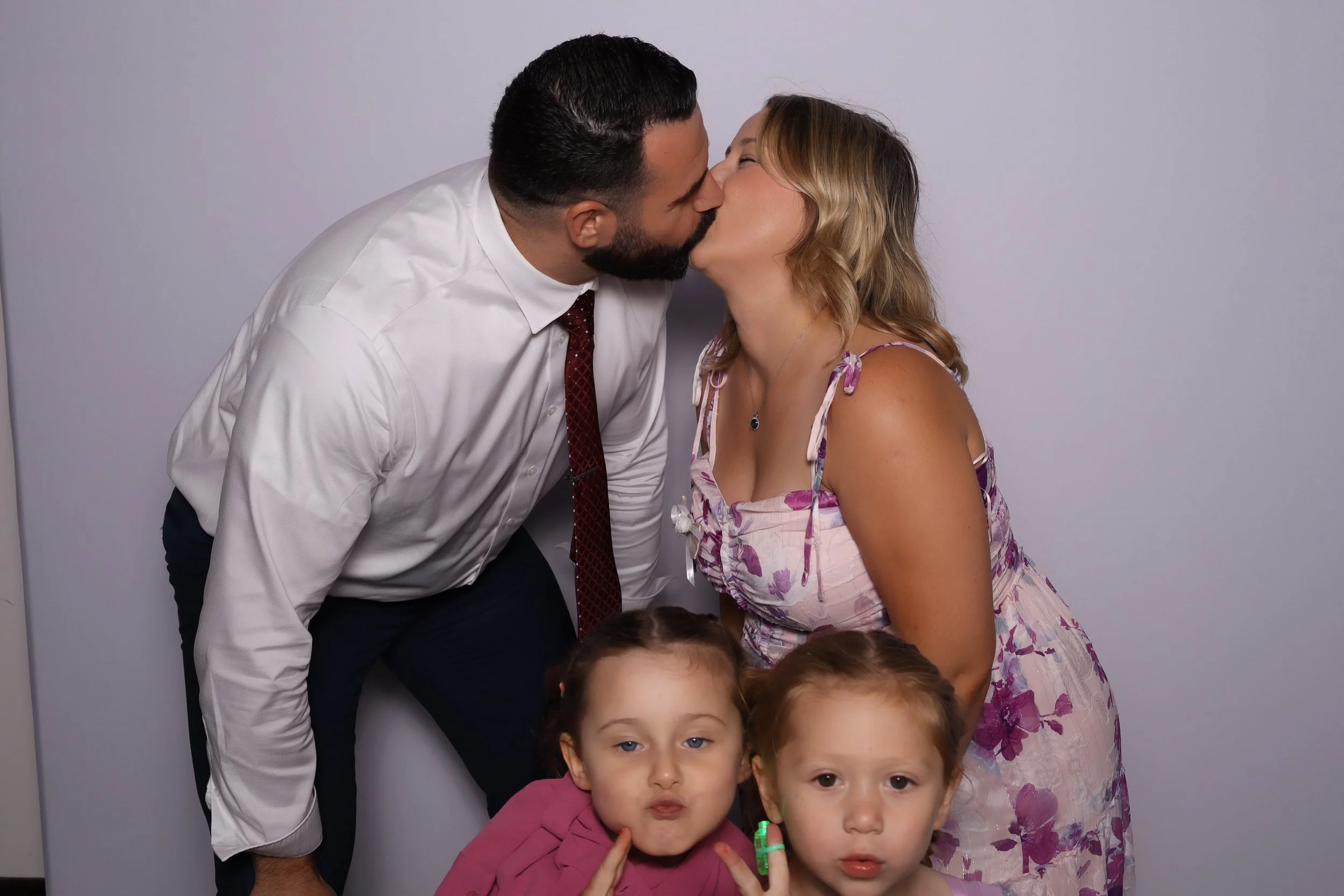 A couple kissing, two young girls in front, posing for the camera