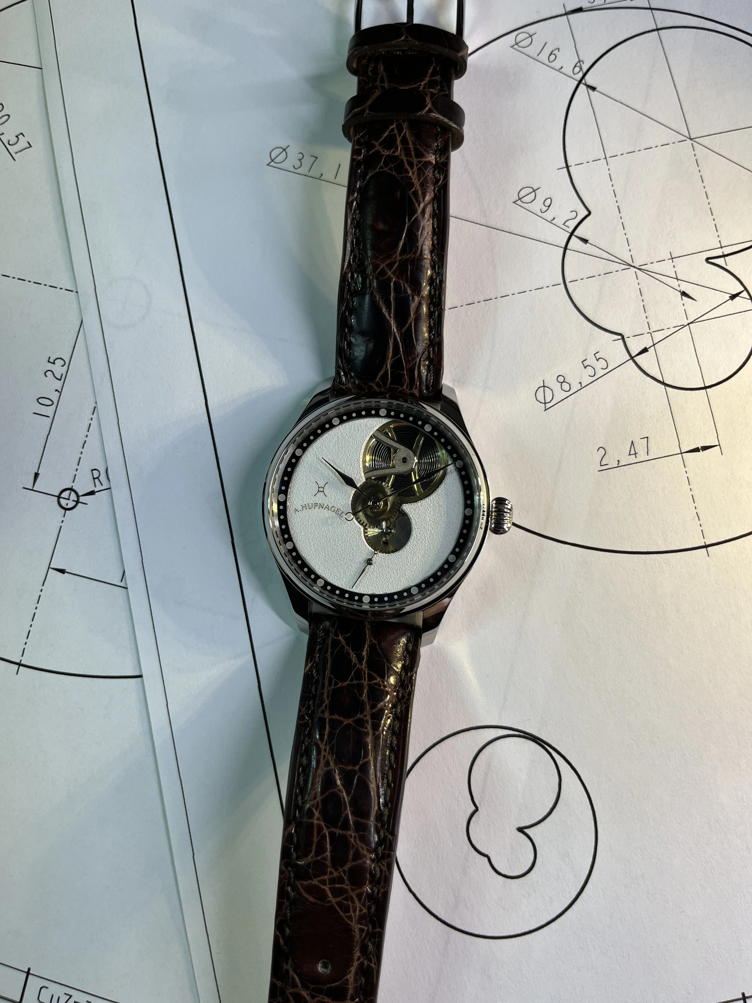 Eine Armbanduhr mit durchsichtigem Zifferblatt, das Zahnräder und Mechanik zeigt, auf einem weißen Stoff platziert.