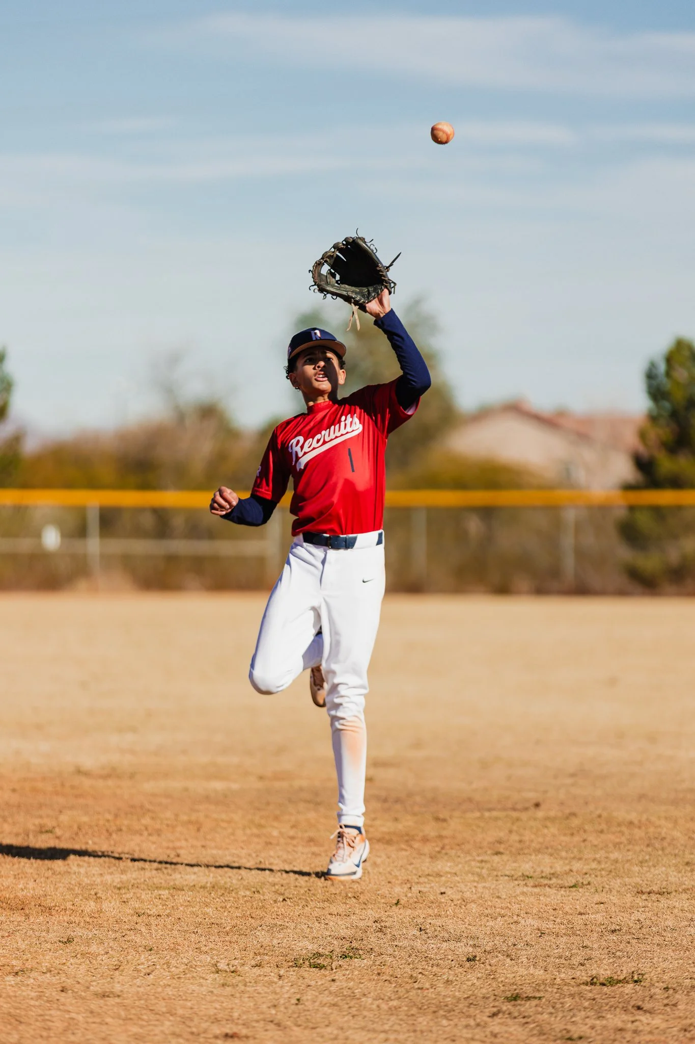 A young baseball player wearing a red jersey with 