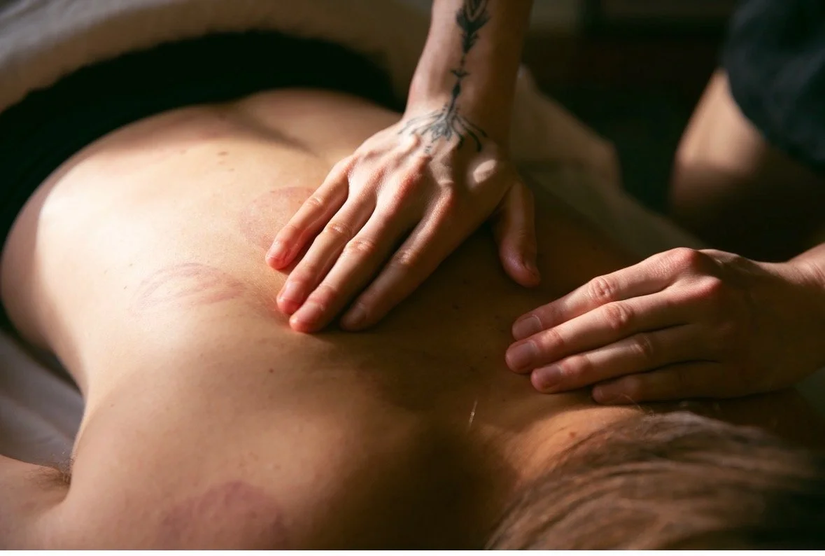 A person receiving a massage on their back, with the massage therapist's hands pressing into the skin.