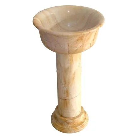 A marble-topped pedestal with a cylindrical base and a bowl-shaped top, made of beige-colored onyx or marble.