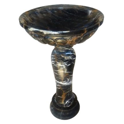 A decorative marble or stone pedestal or bowl with a round, shallow top and a narrow carved base.