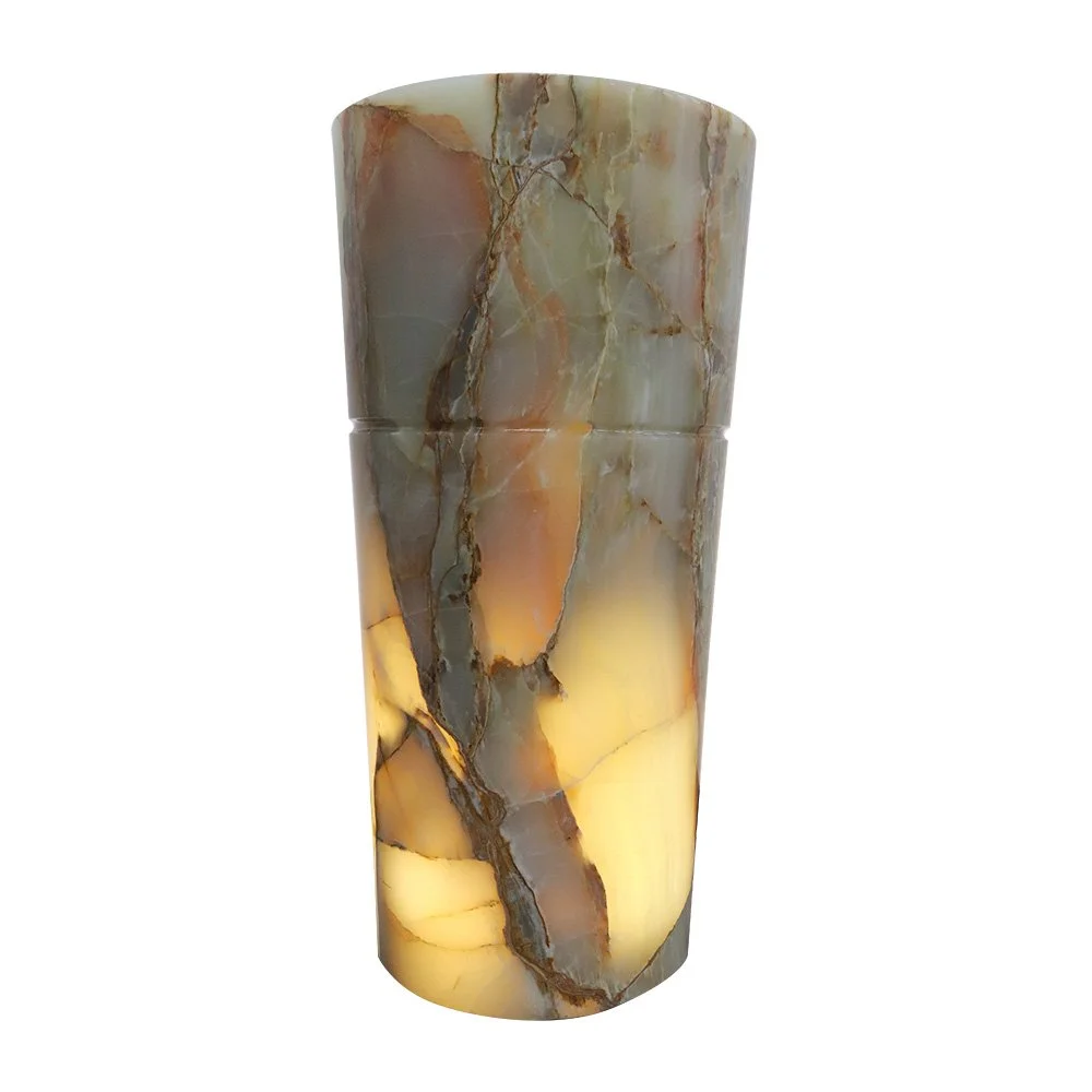 A tall cylindrical marble lamp with a warm glow inside, featuring a mix of beige, brown, gray, and orange tones and natural veining patterns.