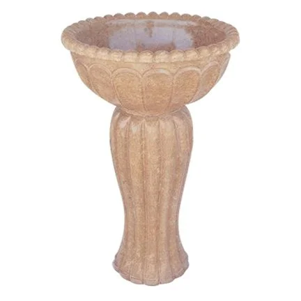 A stone or concrete pedestal birdbath with a wide, scalloped edge.