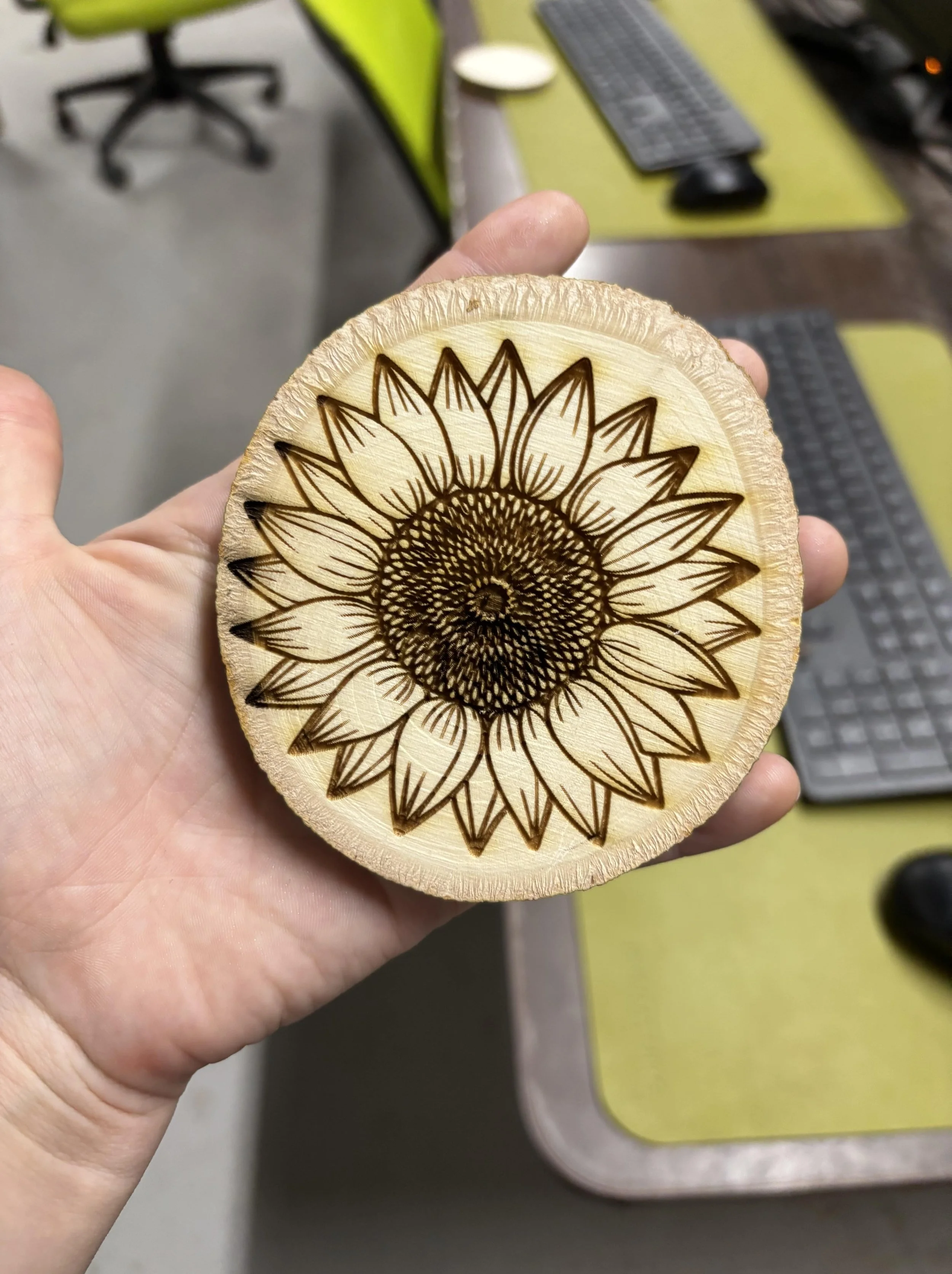 Wooden disk with a sunflower design burned into it, featuring detailed petals and a central spiral pattern.