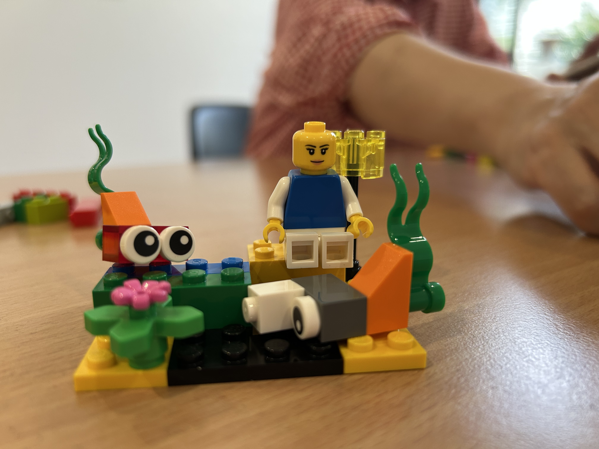 LEGO model with flowers, googly eyes and minifigure sitting on block