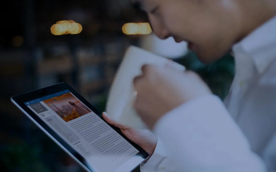Person looking at a digital device reading an article or blog post about a person on a beach at sunset.