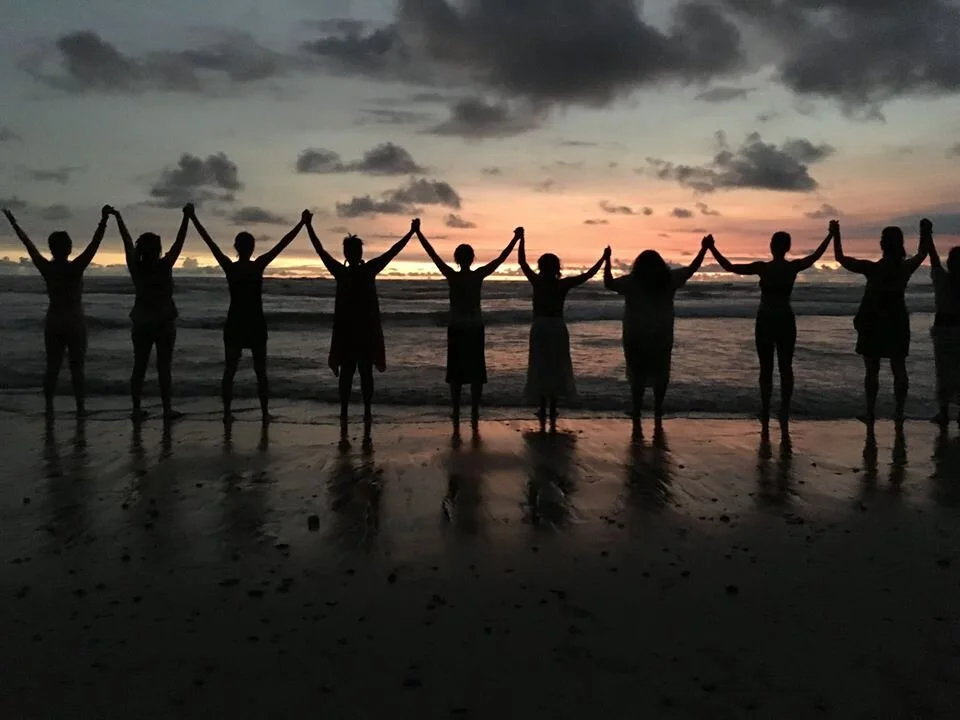 Women holding hands in a circle on the beach at sunset - from WisdomWomen's retreat at Blue Spirit Retreat Center in Nosara, Costa Rica.
