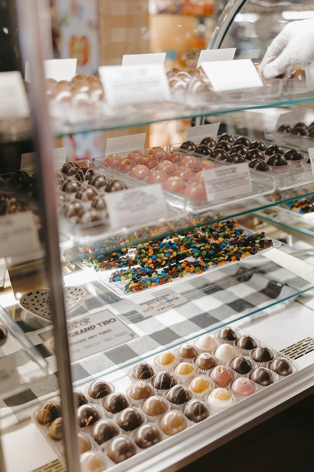 Display case of assorted chocolates and candies with various colors and fillings.