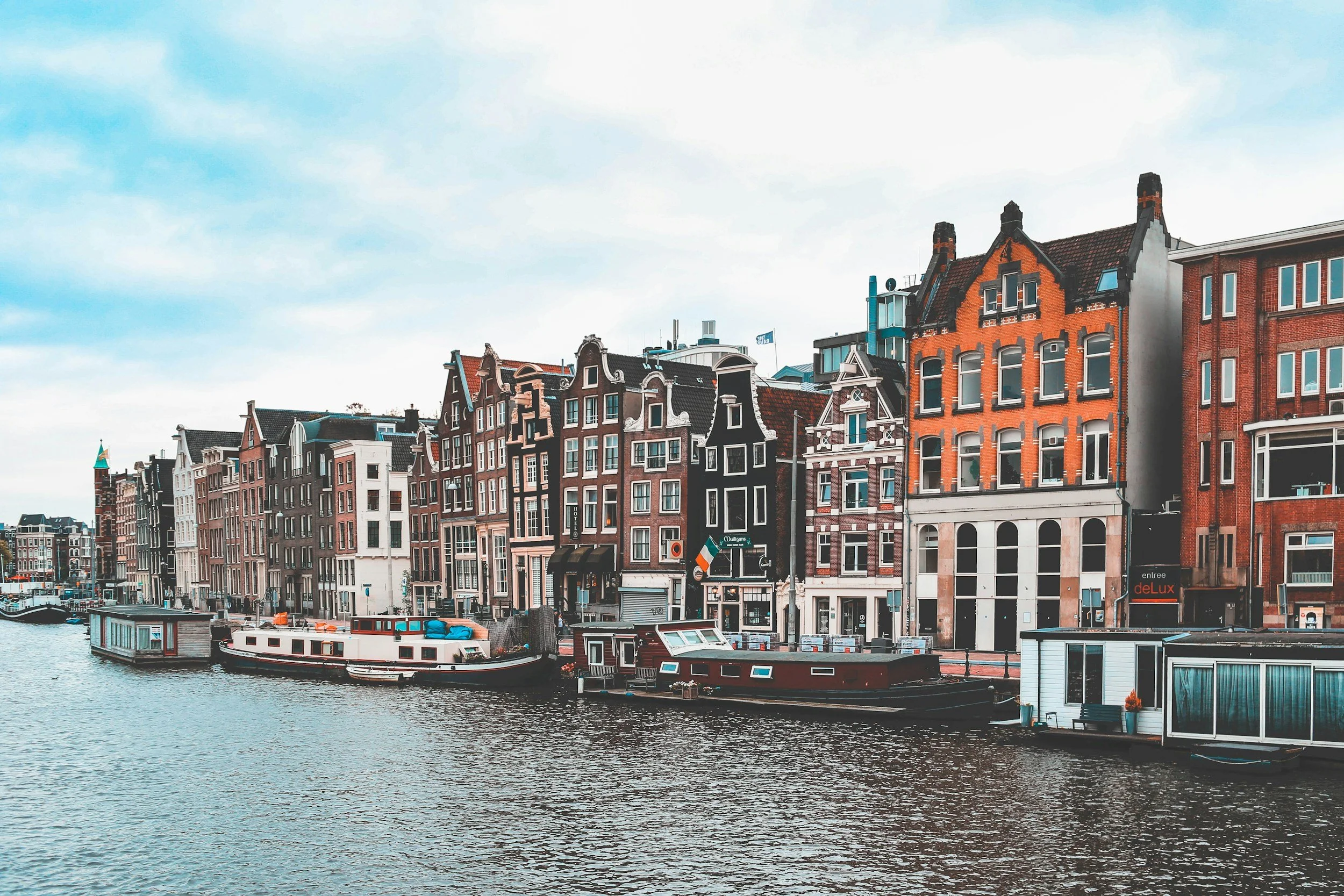 Colorful European-style buildings along a canal with boats docked in Amsterdam.
