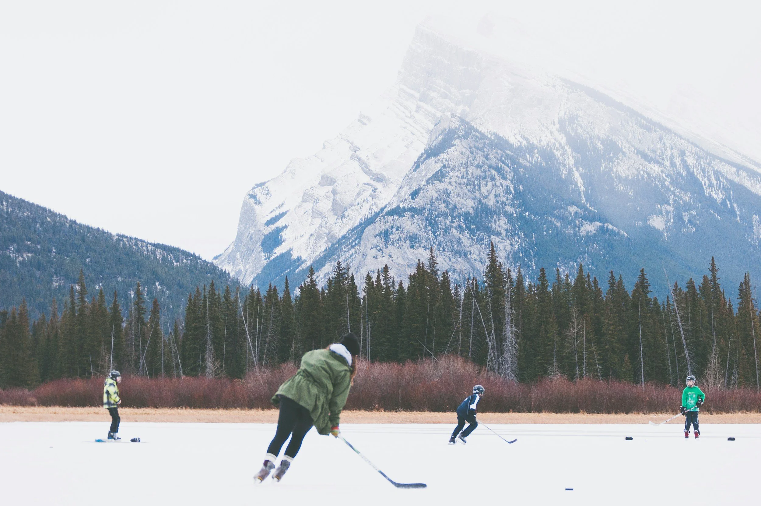 Canadian students  playing hockey on an outdoor ice rink with canada mountains in the background.