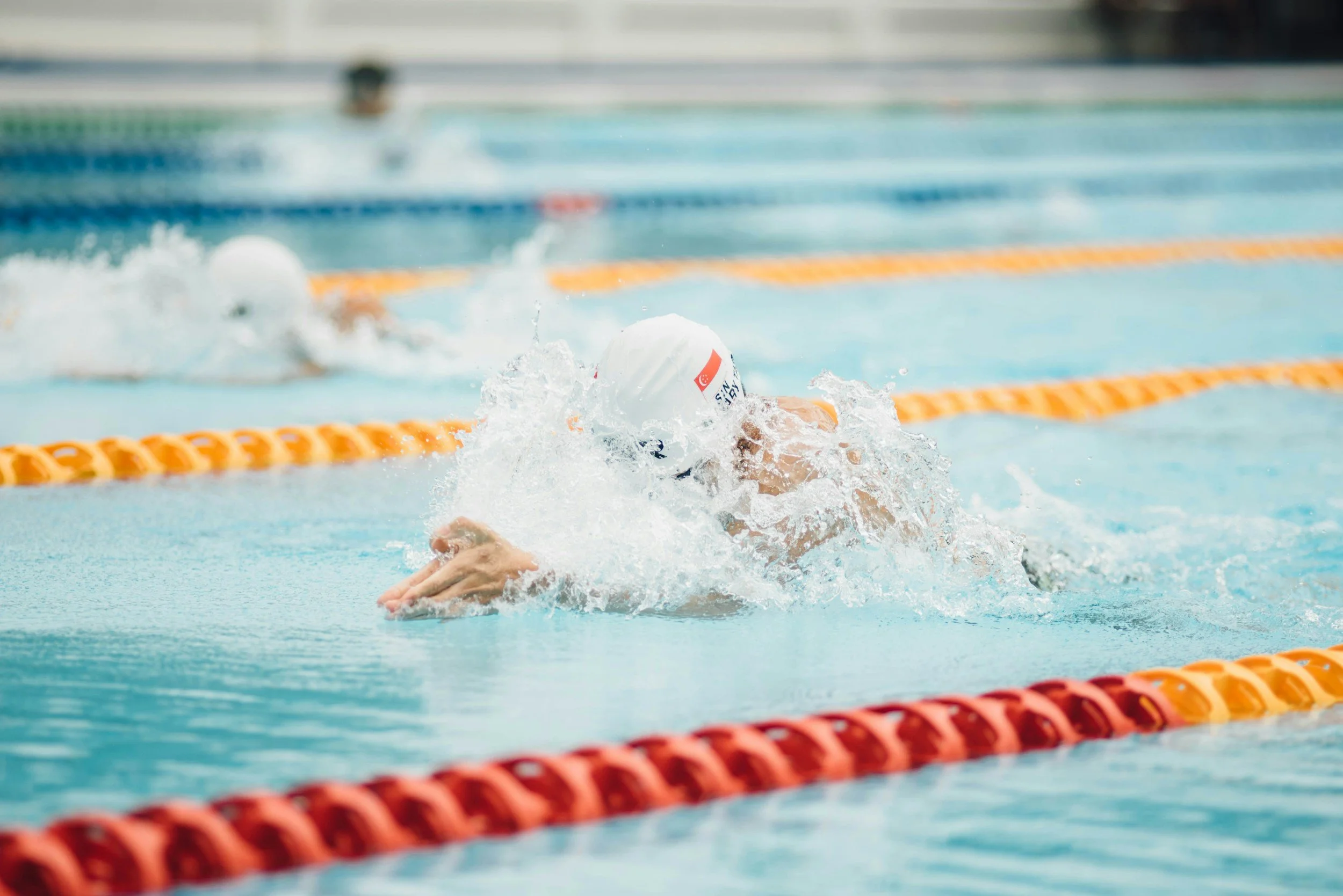 USA college swimmer competing in a swimming race, swimming freestyle in a pool with orange lane dividers.