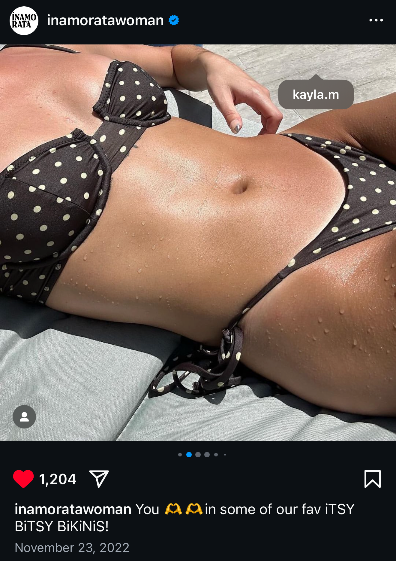 Person wearing a black polka dot bikini, sunbathing on a gray surface, with water droplets on their skin, tagged as 'kayla.m'. Photo posted by Inamorata Woman.