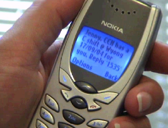Close-up of hand holding a Nokia mobile phone displaying a text message on the screen.