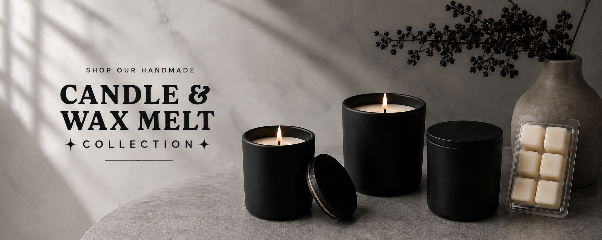 **Alt text:** Handmade matte black candles and wax melts arranged on a neutral stone surface, featuring lit candles, black lids, and a six-cube wax melt tray.