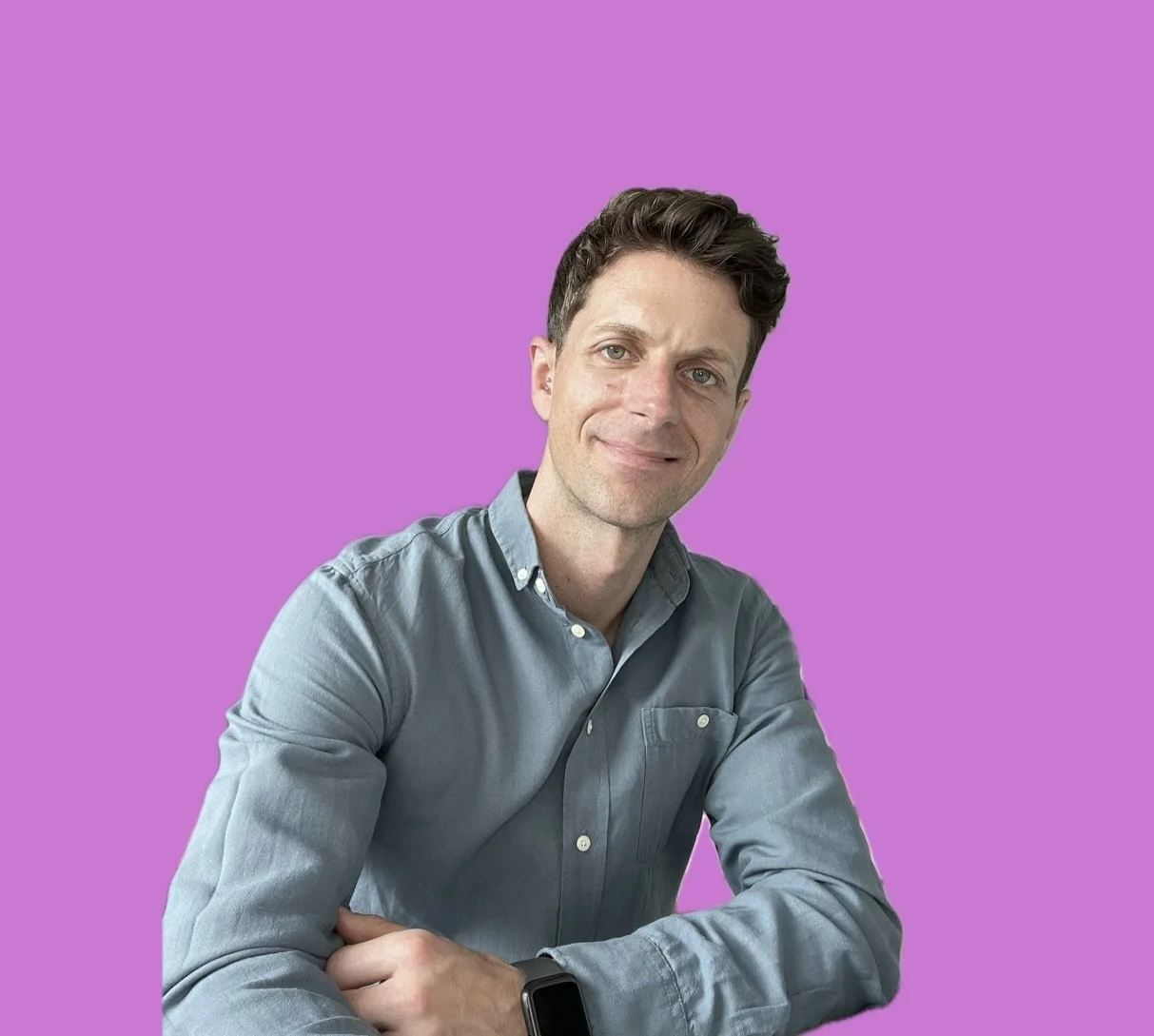 Person in einem blauen Hemd vor einem pinken Hintergrund.