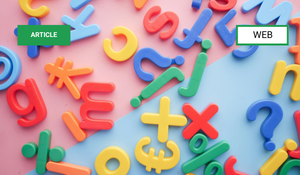 Colored plastic numbers and mathematical symbols scattered on a white surface.