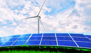 Wind turbine behind solar panels in a grassy field under a partly cloudy sky