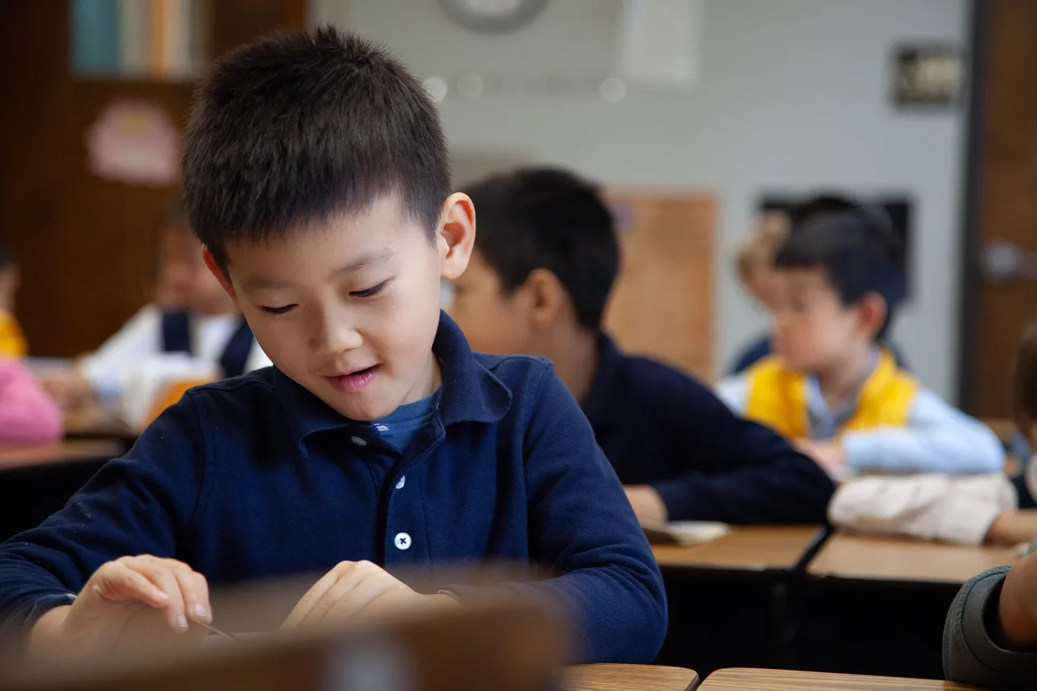 A Little Lotus Academy student working at his desk in a small classroom