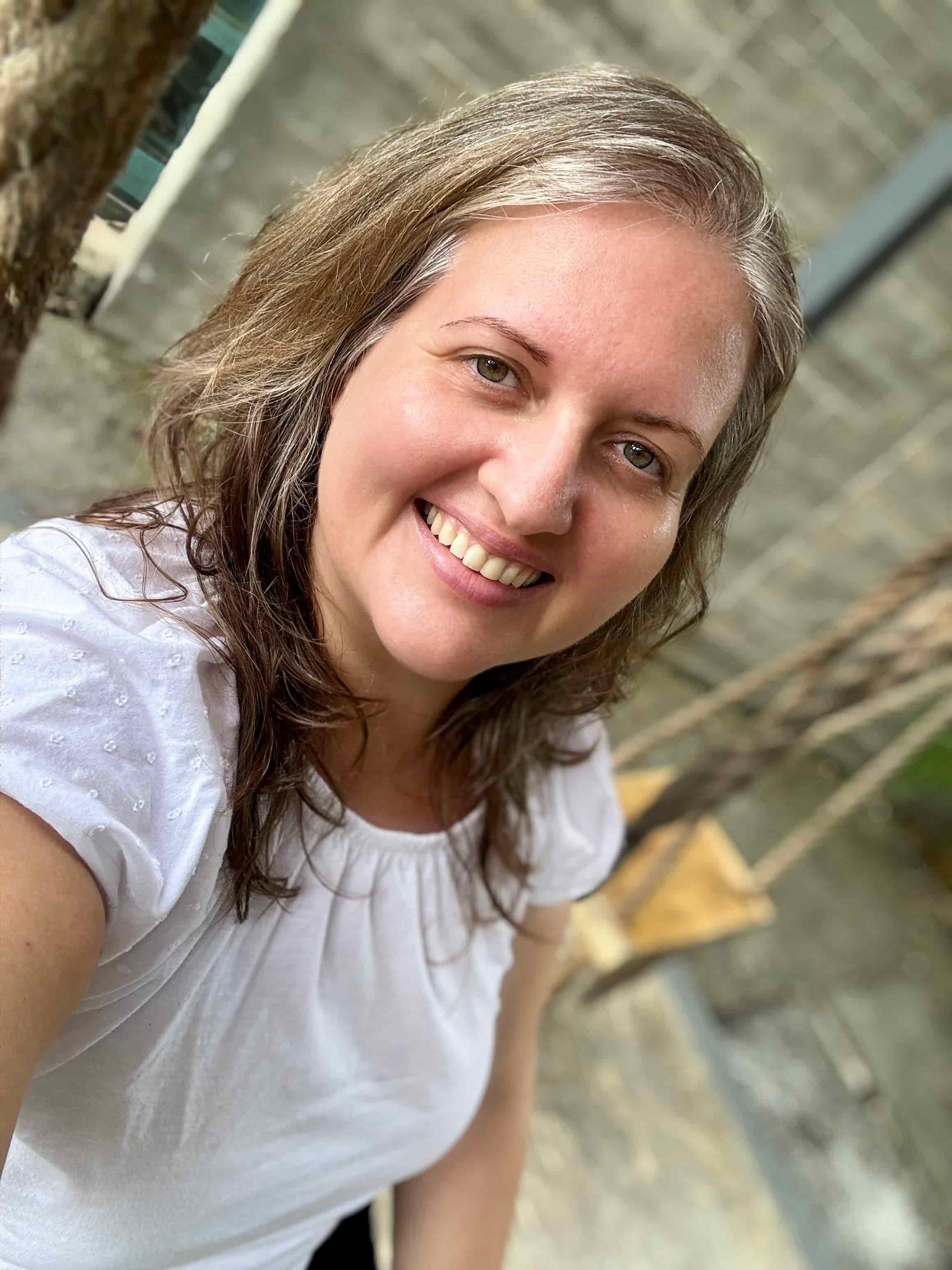 Karina Ramirez, safe space facilitator and relationship coach, sitting on a swing in Tulum wearing a white dress and smiling softly
