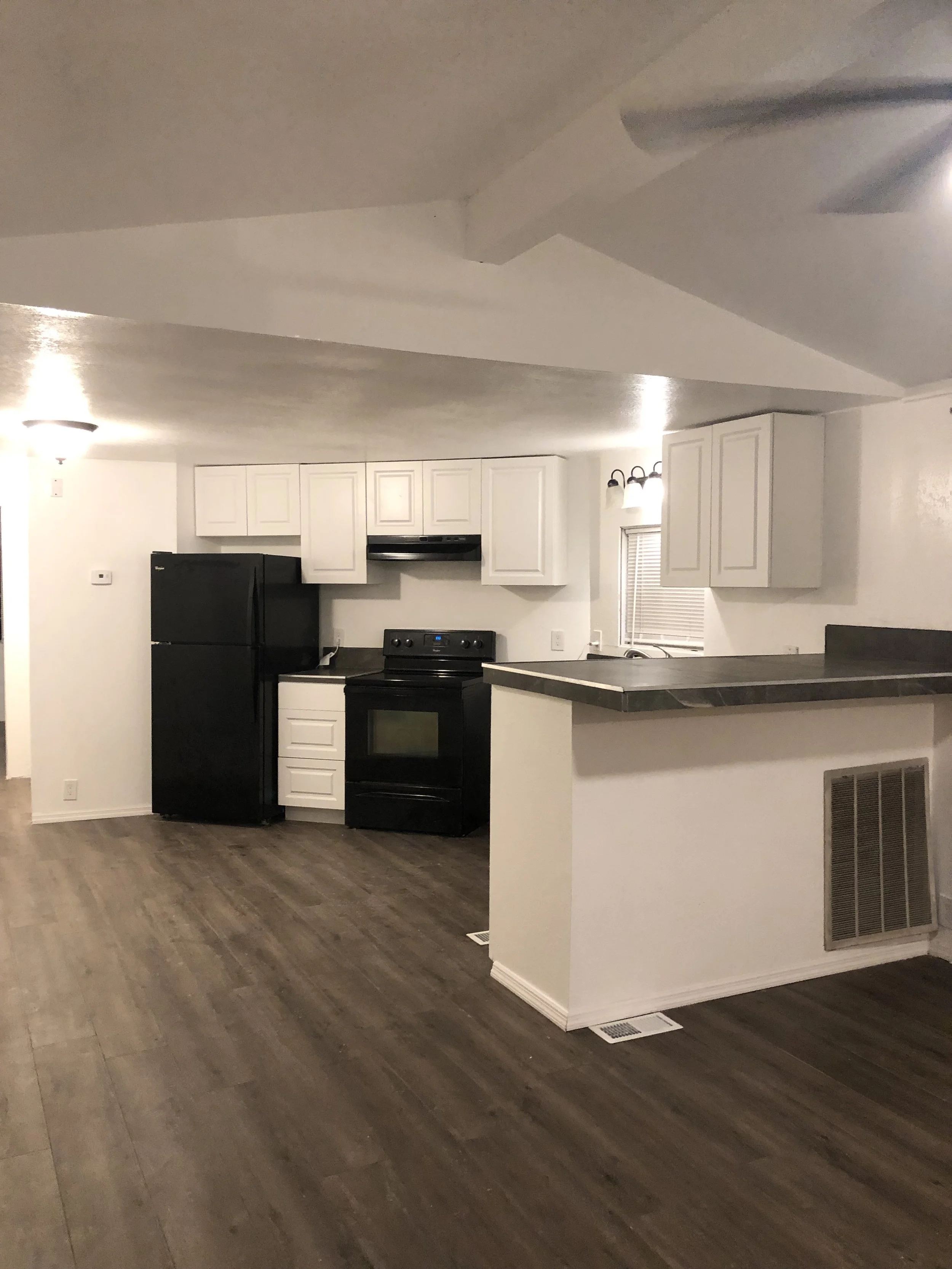 Modern kitchen with white cabinets, black appliances, and wood flooring