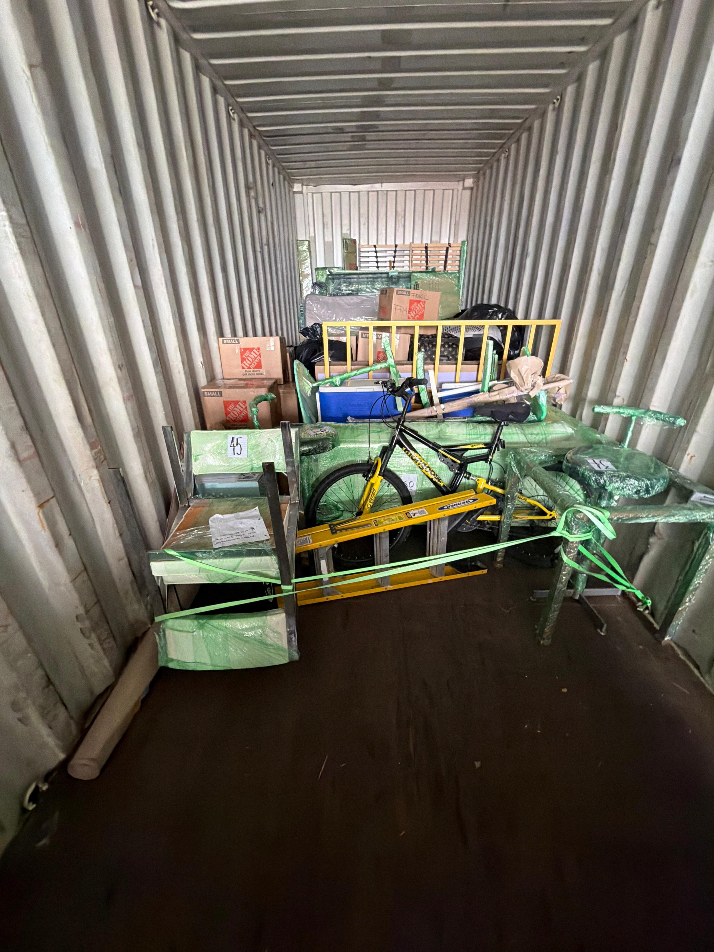 Storage unit filled with boxes, furniture, a bicycle, and miscellaneous items