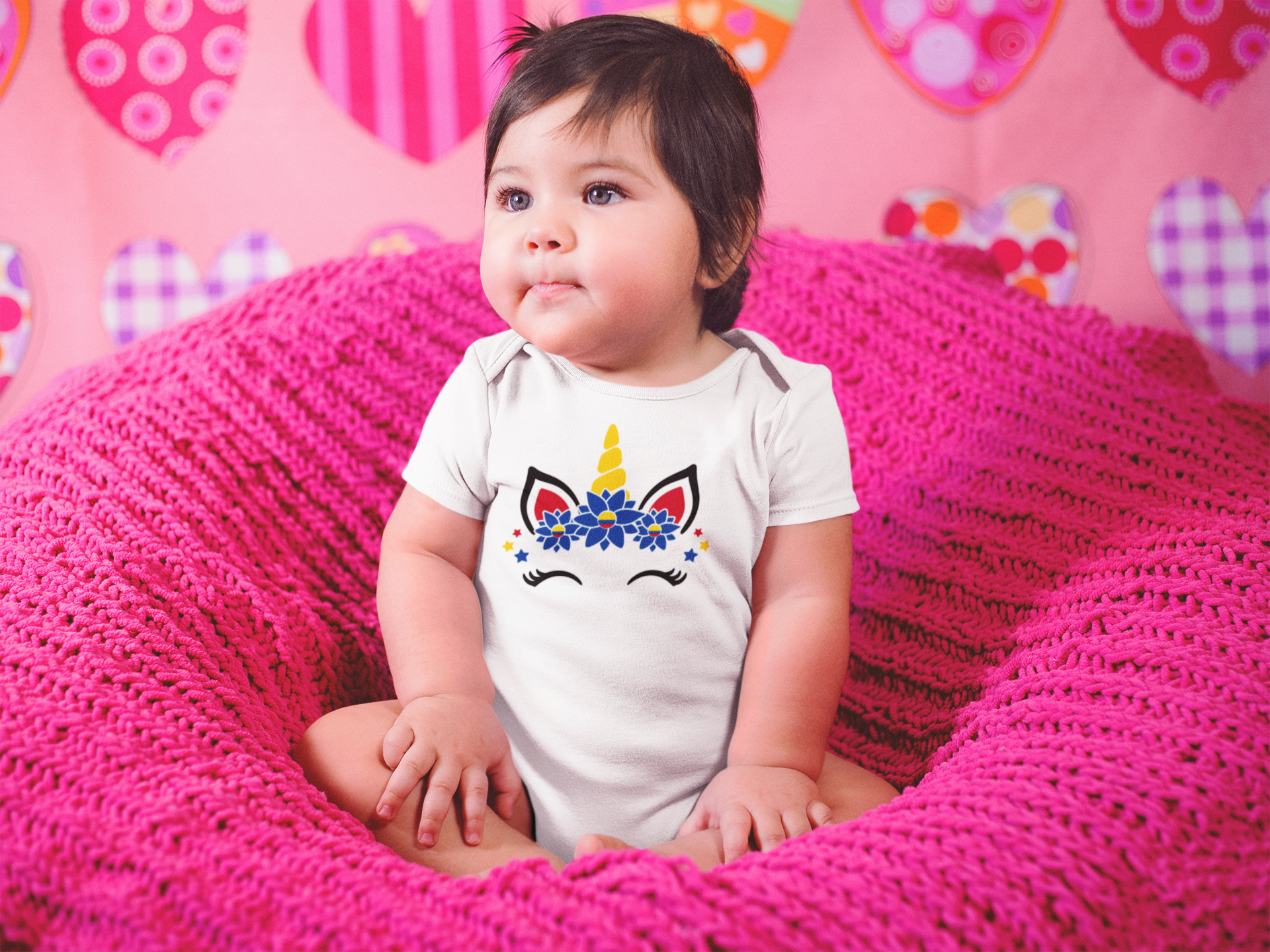 beautiful-little-baby-girl-sitting-on-a-pink-sofa-while-wearing-a-onesie-a14047--2.png