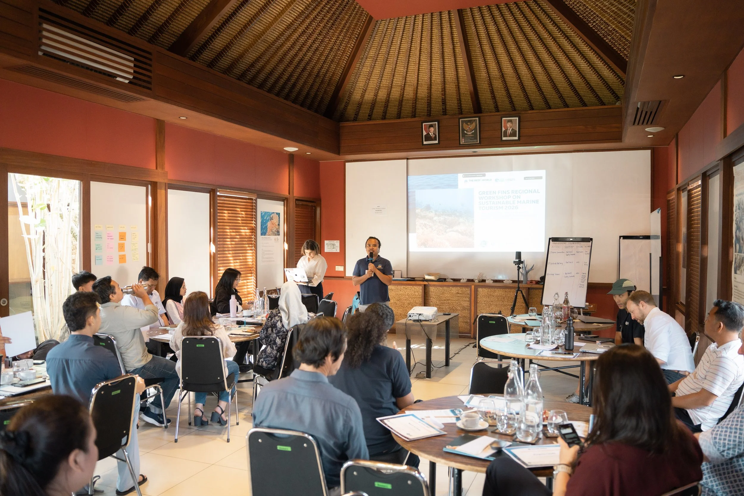 A light airy meeting room with facilitator leading discussion with delegates.