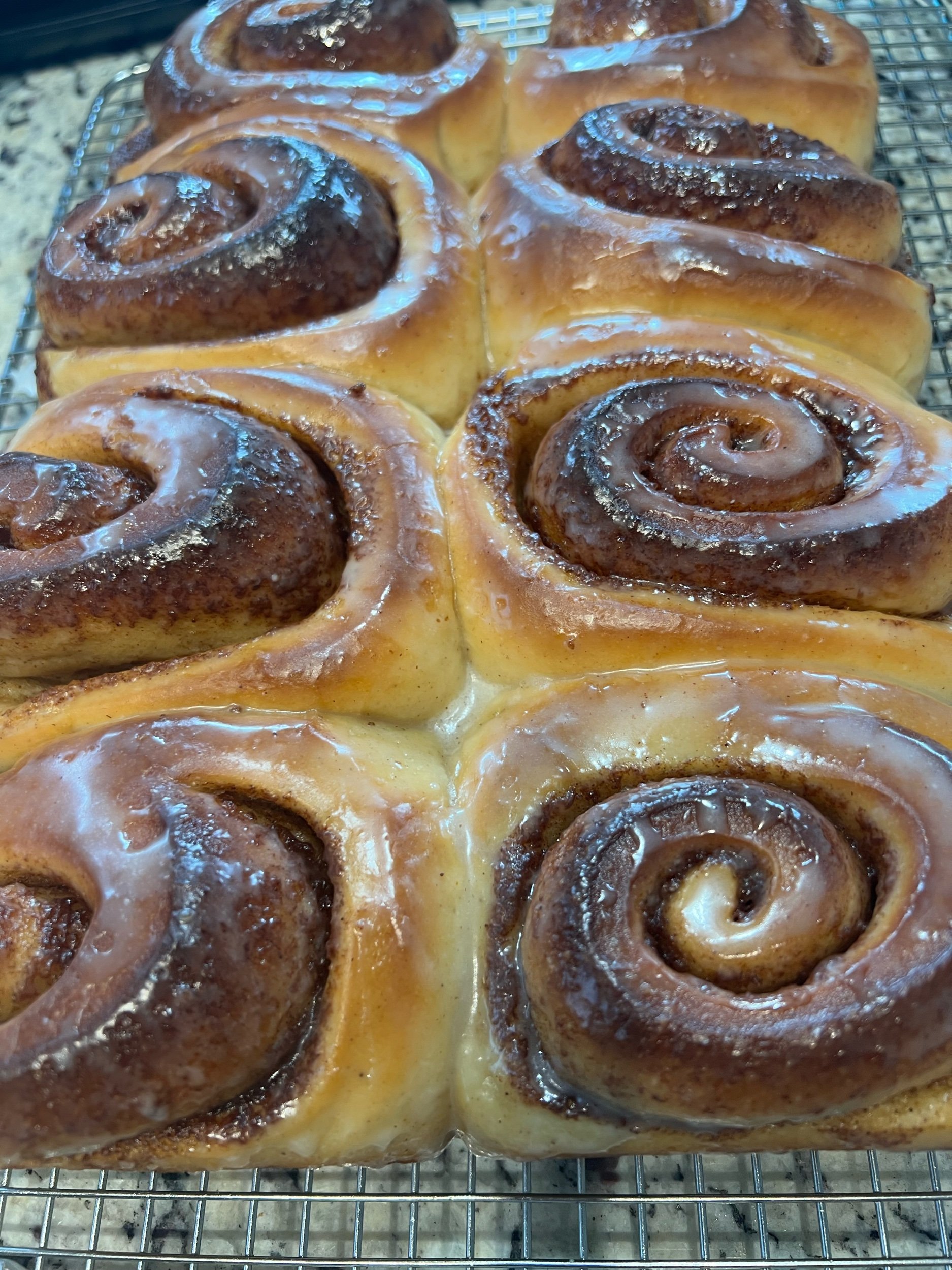 Gertrudis Panem Vitas sourdough cinnamon rolls with golden crust and light glaze, arranged in an 8-piece box