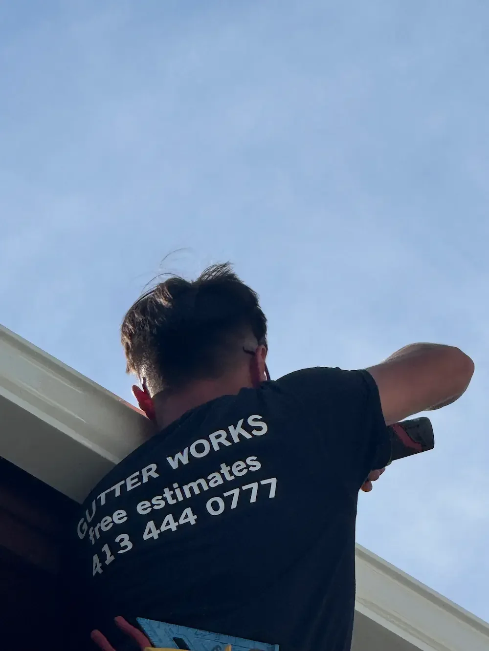 Contractor cleaning roof gutters during gutter maintenance service