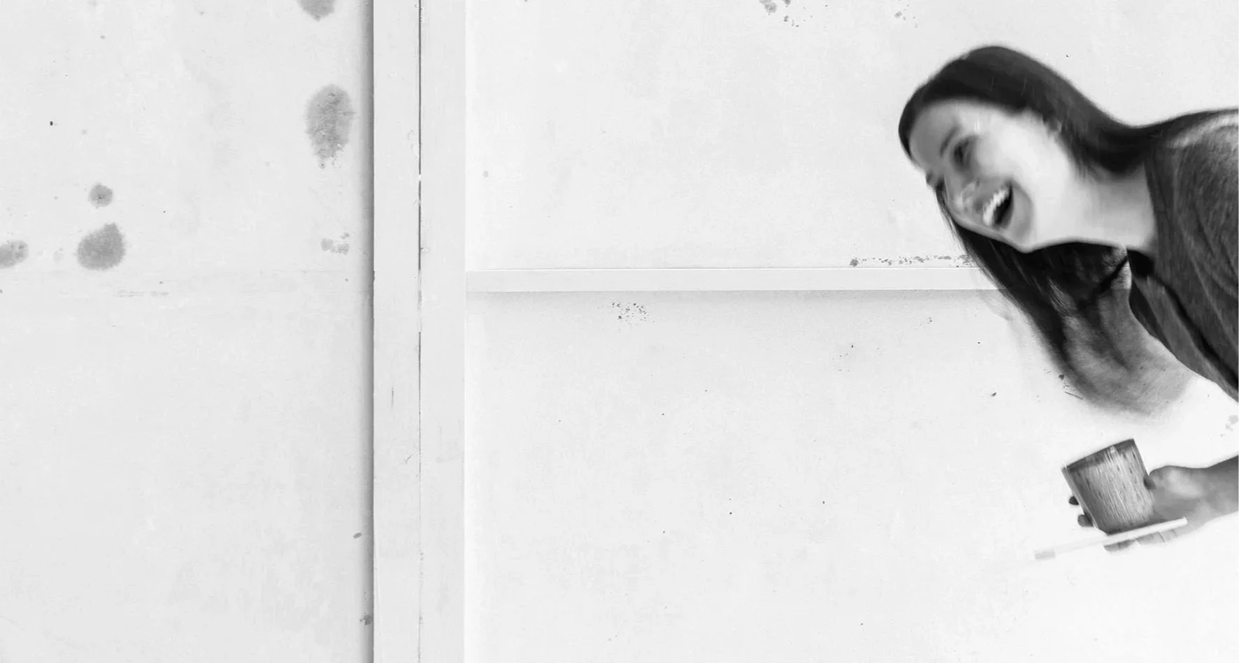 Grafikerin Melanie Pototschnig lacht aus dem rechten Bildrand hinein. Sie hat eine Kaffeetasse und ein Handy in der Hand.