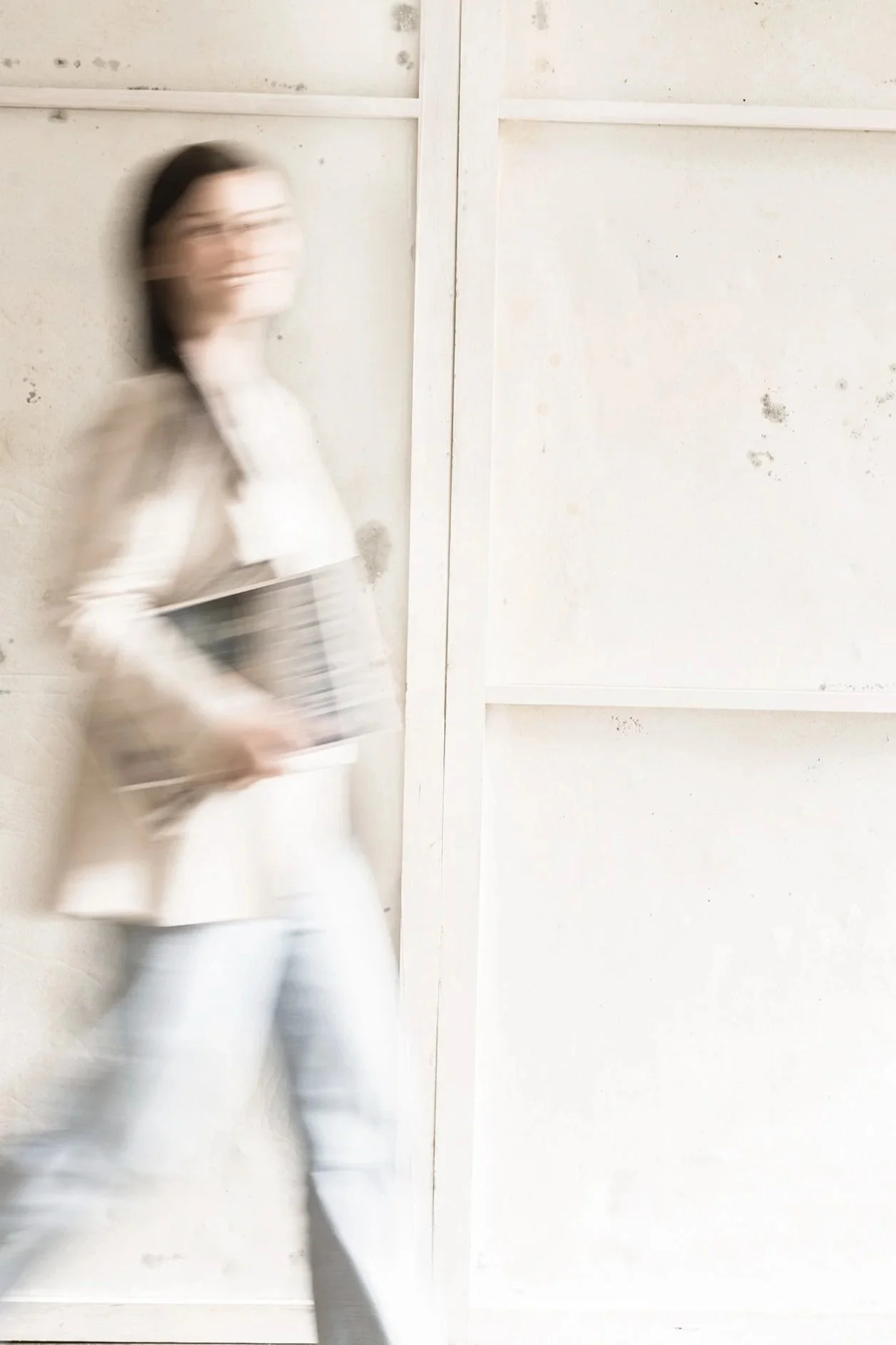 Grafikerin Melanie Pototschnig läuft lachend vom linken Bildrand Richtung rechten Bildrand. Das Bild ist durch die Bewegungsunschaerfe verschwommen und in einem warmen beige ton gefärbt.