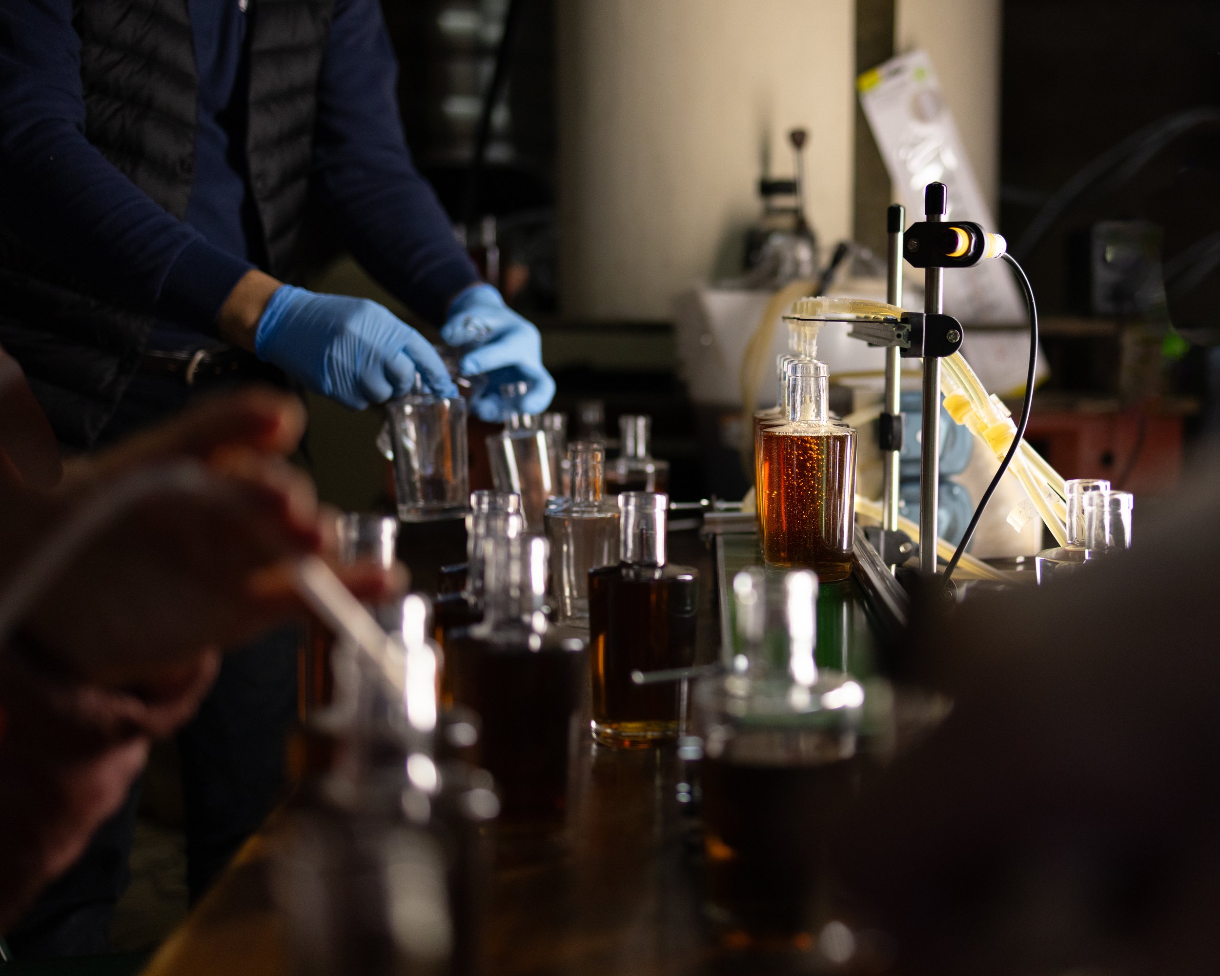 Procédé de laboratoire avec des flacons contenant des liquides distillés, des pipettes, et une personne portant des gants bleus manipulant des échantillons.