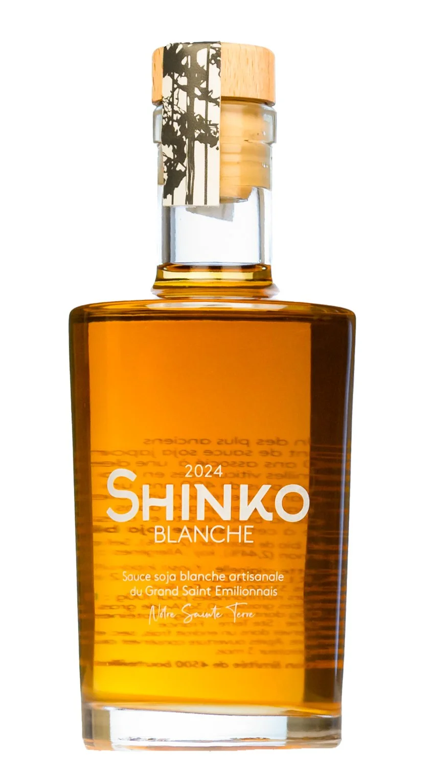 Bouteille de sauce soja blanche, artisanale, avec un bouchon en bois, portant une étiquette blanche et noire avec un arbre