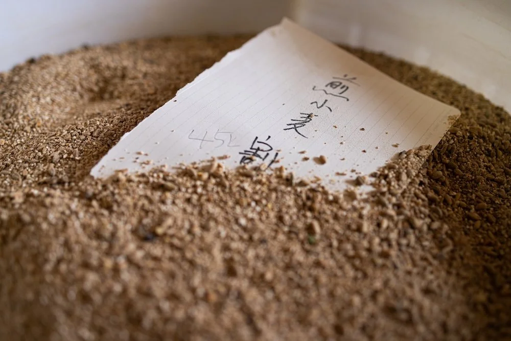 Note de papier en bois avec écrit en chinois, partiellement enterrée dans du sable ou de la terre