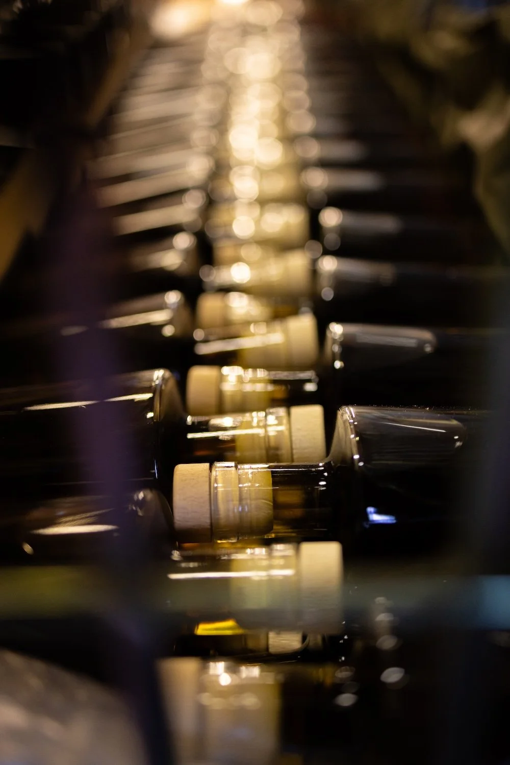 Une vue rapprochée d'une palette de bouteilles de sauce soja française maison shinko noire et blanche, éclairée par une lumière chaleureuse. La sauce soja française de la maison shinko de Sainte Terre en Gironde